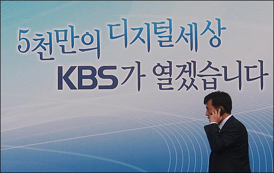 지난 2011년 7월 11일, 서울 여의도 KBS 본관 앞에서 한 시민이 KBS 수신료와 관련된 광고판 앞을 지나가고 있다.