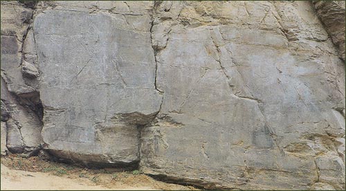 ‘ㄱ’자 모양으로 꺾인 절벽암반에 여러 가지 모양을 새긴 바위그림
