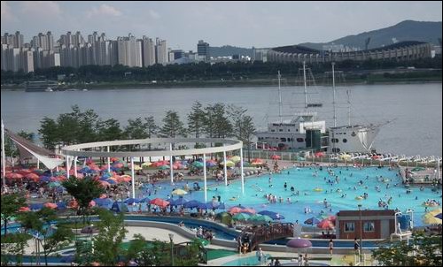 뜨거운 햇살 아래 한강변 수영장을 많은 사람이 찾고 있습니다.