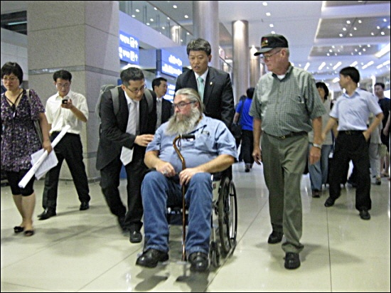 24일 오후 입국한 스티브 하우스씨가 김선동 민주노동당 의원이 미는 휠체어를 타고 숙소로 이동하고 있다. 오른편 모자를 쓴 사람은 필 스튜어트씨.