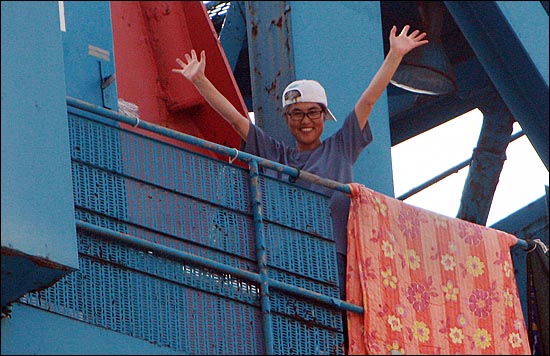 지난 7월 30일 오후 부산 영도구 한진중공업 '85호 크레인'에서 김진숙 지도위원이 지지자들에게 밝은 표정으로 손을 흔들어 보이며 인사하고 있다.