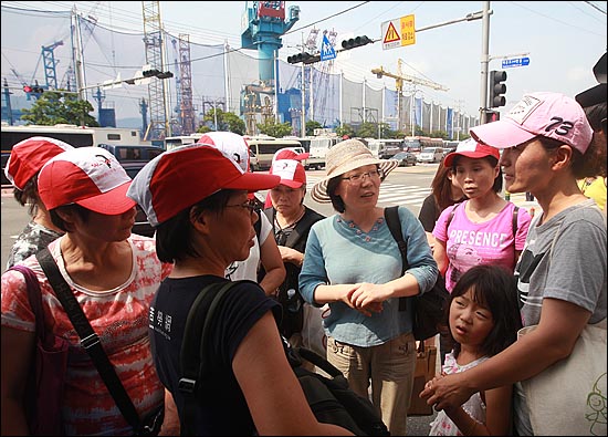 '3차 희망버스' 행사에 참여한 홍콩여성노동자모임 소속 노동자(빨간모자)들이 30일 오후 부산 영도구 한진중공업 '85호 크레인' 앞에서 정리해고 철회를 요구하며 한진중공업 가족대책위 회원(맨 오른쪽)을 격려하고 있다.