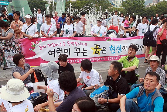 30일 오후 부산역 광장에서 열린 '사람 살리고, 한진중공업 정리해고 철회를 위한 3차 희망버스 환영문화한마당'에서 한진중공업 가족대책위 회원들이 현수막을 들어보이며 희망버스 참가들을 환영하고 있다.