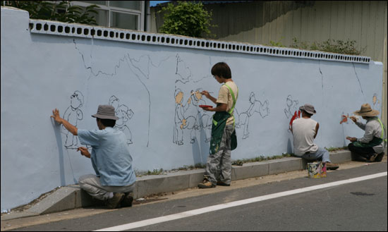 이재관(맨 왼쪽) 씨와 그의 아들, 그리고 동료 귀농자들이 곡성군 목사동면 평리마을에서 마을벽화 그리기 작업을 하고 있다.