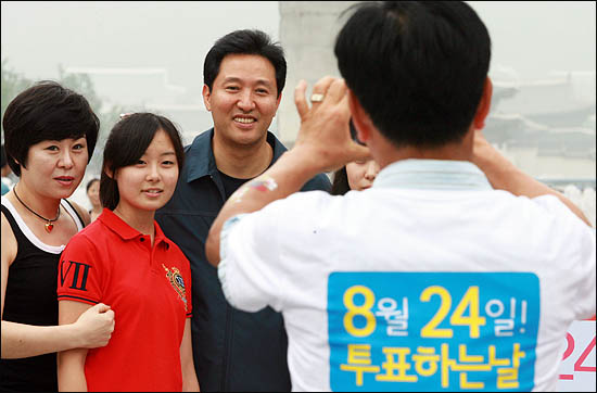 무상급식 주민투표 참여를 호소하기 위해 15일 오후 서울 광화문 이순신장군 동상 앞에서 일인시위에 나선 오세훈 서울시장이 거리를 지나던 시민들과 기념촬영을 하고 있다.