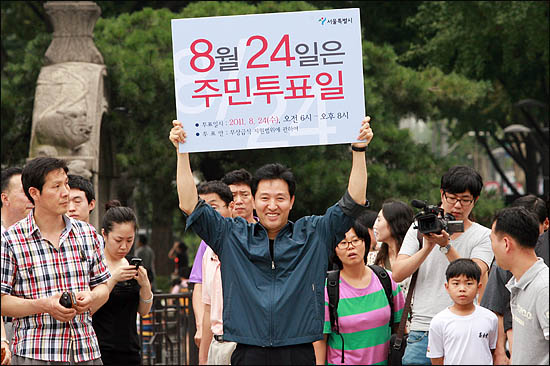 무상급식 주민투표 참여를 호소하기 위해 15일 오후 서울 광화문 일대를 돌며 일인시위에 나선 오세훈 서울시장이 거리를 지나던 시민들을 향해 주민투표일을 알리는 피켓을 들어보이고 있다.