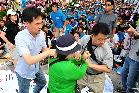 민주당 정동영 최고위원을 폭행한 여성이 행사관계자들에게 붙잡혀 끌려 나오고 있다.