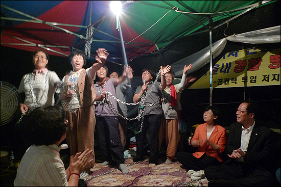 '쇠사슬 시스터즈'라고 이름을 자칭한 쇠사슬 투쟁을 벌이고 있는 강정마을 주민들이 축하공연을 하고 있다.