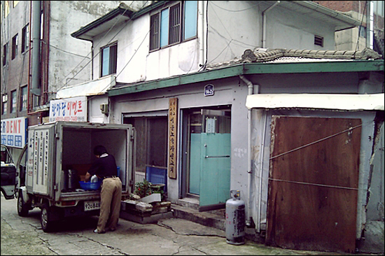 교북동 골목 모퉁이에 자리한 서울노숙자선교회 앞에서 한 자원봉사자가 급식을 싣고 있다.