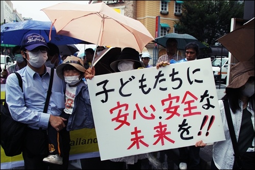 7월31일 후쿠시마시에서 열린 탈핵을 요구하는 행진에서 참가자들이 "아이들이 안심하고 안전할 수 있는 미래를 보장하라"는 내용의 피켓을 들고 있다.