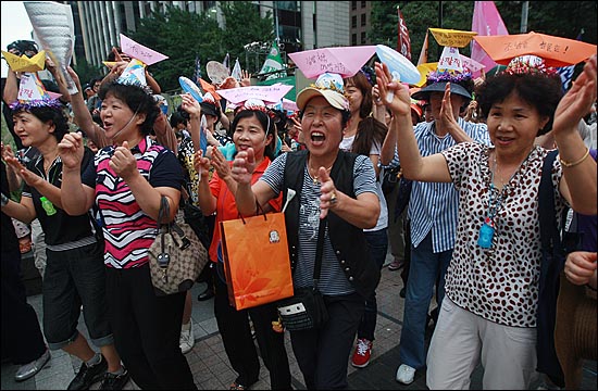  2011년 8월 27일 오후 서울 종로구 청계광장에서 열린 '한진중공업 정리해고 철회를 위한 4차 희망버스 만민공동회'에서 희망버스 참가자들이 비정규직 노동자들의 염원을 담은 '희망의 종이배'를 머리에 쓰고 풍물놀이를 지켜보며 즐거운 시간을 보내고 있다.