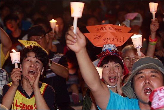  27일 오후 서울 종로구 청계광장에서 열린 '한진중공업 정리해고 철회를 위한 4차 희망버스 만민공동회'에서 희망버스 참가자들이 촛불을 들어보이며 한진중공업 정리해고 철회 등을 외치고 있다.