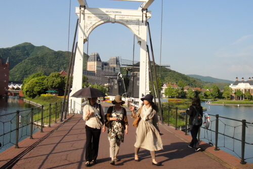 일본 규슈의 유명 관광지 하우스텐보스에 나들이 나온 여성들이 검은색 양산과 챙이 넓은 모자를 쓰고 있다. 