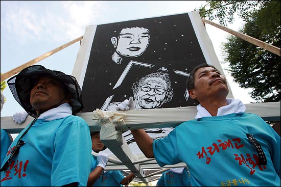 부산 한진중공업 해고노동자들이 전태일 열사가 어머니 이소선씨의 영정사진을 들고 있는 대형 판화그림을 옮기고 있다.