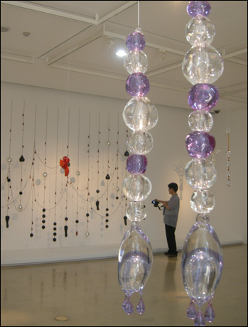  '매달린 연인들(The Hanging Lovers)' 80×15×15cm 1999(앞). '검은 마음 붉은 눈물(Black Heart Red Tears)' 391×432×20cm beads, Murano glass 2007 ⓒ Galerie Perrotin(Guillaume Ziccarelli) 
