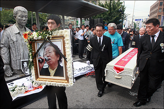 '노동자의 어머니 이소선 민주사회장'이 엄수된 7일 오후 서울 청계천 평화시장 앞 '전태일 다리'에서 열린 노제에서 고인의 영정사진과 운구가 아들의 동상 앞을 지나가고 있다.