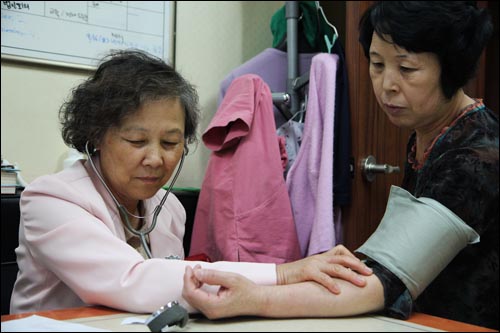 자원봉사자가 중국동포 환자의 혈압을 체크하고 있다.