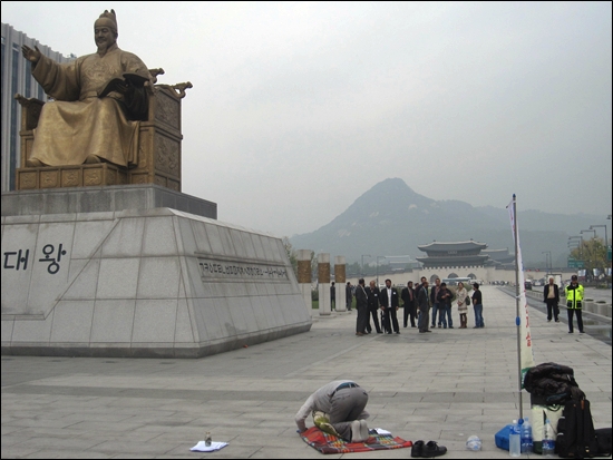 15일, 광화문 광장 세종대왕상 앞에서 목원대생 김아무개씨가 1만 배 하는 것을 외국인 관광객들이 지켜보고 있다. 