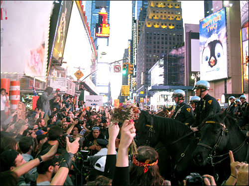 '월스트리트 점령' 시위대가 지난 2011년 10월 15일 오후 뉴욕 맨해튼 타임스퀘어에 모여 시위를 벌이자, 기마경찰이 출동해 시위대를 위협하고 있다. 시위대는 손가락으로 평화를 상징하는 'v'를 만들었고, 한 시위 여성은 꽃을 들고왔다.
