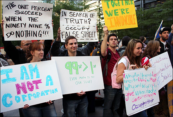 '월스트리트 점령' 시위가 진행 중인 뉴욕 맨해튼 자유광장(주코티파크) 앞에서 시위대들이 시민들을 향해 '99%가 1%보다 크다' 등의 구호가 적힌 손팻말을 들고 서 있다.