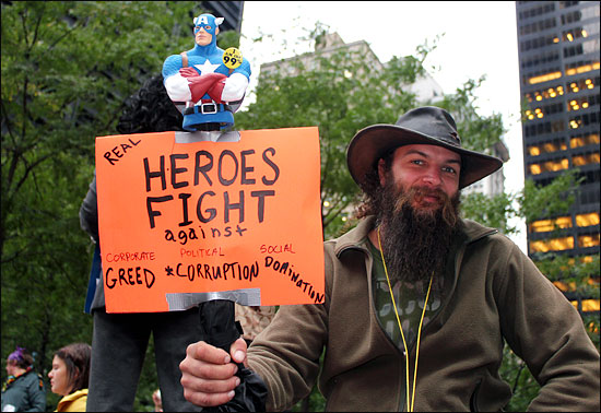 '월스트리트 점령' 시위가 진행되고 있는 뉴욕 맨해튼 자유광장(주코티파크)에서 한 시위대가 '진짜 영웅의 적은 기업의 탐욕'이라는 내용의 손팻말을 들고 서 있다.
