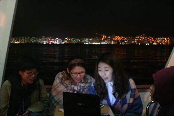 도시의 불빛을 배경으로 PPT 작업에 열중하고 있는 참가자들