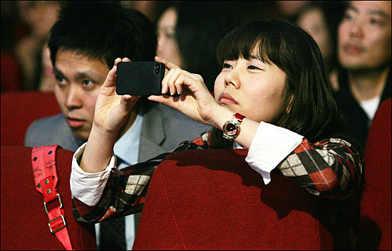Mnet <슈퍼스타K3> TOP4 5번째 <심사위원 명곡 미션>을 방청하던 한 관객이 스마트폰을 이용해 사진을 찍고 있다.