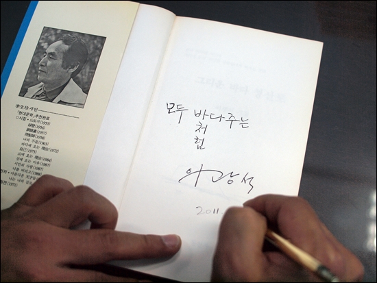 가수 이광석이 자신이 소장하고 있던 이생진 시인의 <그리운 바다 성산포>를 '책 나눔 캠페인'에 기부하기 전에 서명하고 있다. 