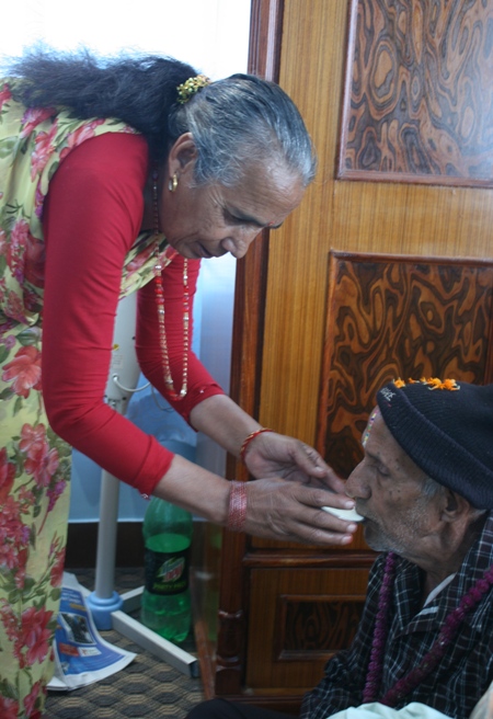 러구의 어머니가 자신의 오빠에게 여러 음식을 대접하기 위해 상을 차려 내놓은 후 소화를 돕는 더위(네팔식 요구르트)를 마시도록 도와주고 있다. 
