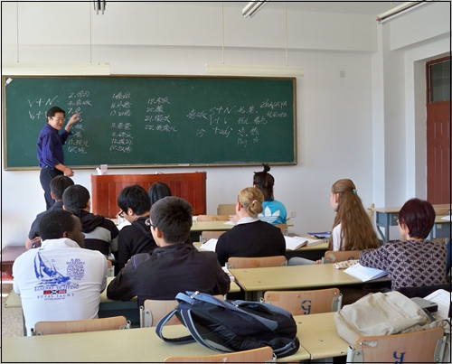 중국어로 진행되는 수업 현장. 노랑 머리와 꼽슬 머리의 외국인 학생이 수업을 듣고 있다.