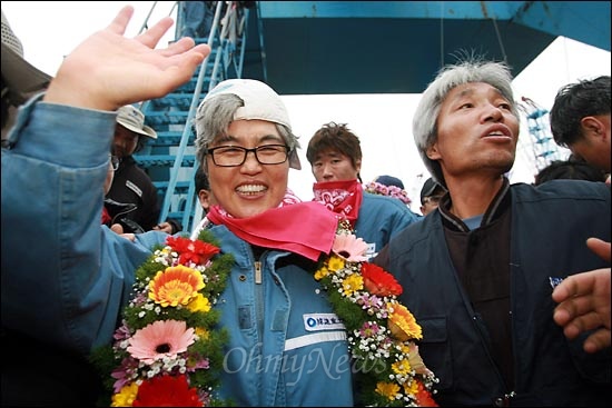2011년 11월 크레인에서 내려온 김진숙 지도위원이 꽃다발을 목에 걸고 동료 노동자와 희망버스 관계자들에게 손을 흔들고 있다.