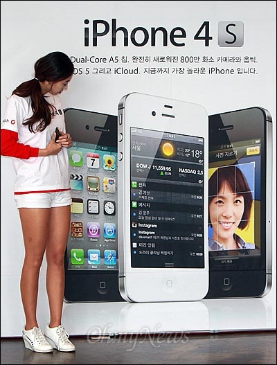 아이폰4S가 KT와 SK텔레콤을 통해 동시 출시된 11일 오전 서울 광화문 KT사옥 올레스퀘어에서 열린 '아이폰4S 런칭 페스티벌'에서 이벤트 관계자가 아이폰4S 출시를 알리는 광고판을 바라보고 있다.