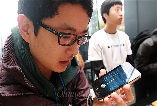 아이폰4S가 KT와 SK텔레콤을 통해 동시 출시된 11일 오전 서울 광화문 KT사옥 올레스퀘어에서 예약가입자인 노규헌씨가 아이폰4S의 기능 중 음성인식 도우미 'siri'를 통해 오늘의 날씨를 확인하고 있다.