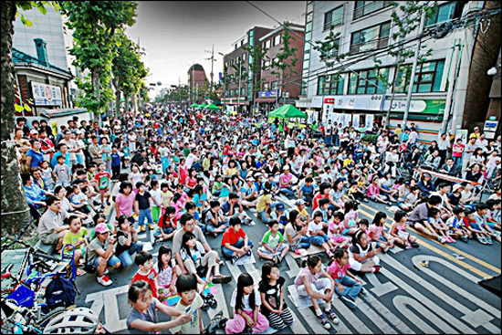 성미산마을 거리를 막고 벌인 축제, 도로위에 주저앉아 많은 주민들의 공연을 즐기고 있다