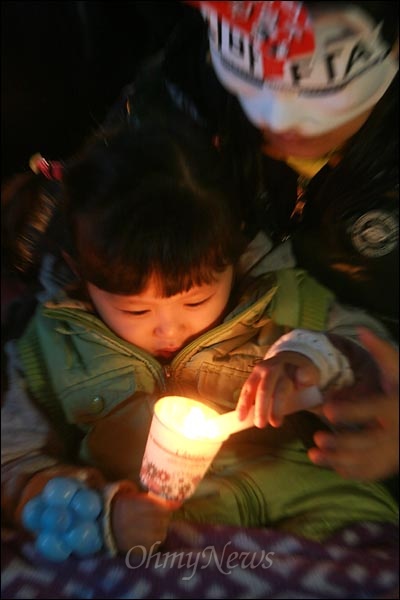 13일 오후 서울광장에서 열린 '한미FTA 저지' 촛불집회에 참석한 한 어린이가 촛불을 켜고 있다.