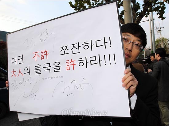 정봉주 전 의원 여권 발급을 촉구하는 구호가 적힌 피켓에 한 팬이 '나는 꼼수다' 멤버들의 사인을 받아 들고 있다.