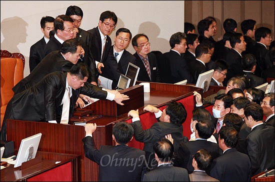  22일 국회 본회의에서 정의화 부의장이 한미FTA 비준안을 기습 상정하자 의장석으로 뛰쳐나간 최규성 민주당 의원이 의사봉 빼앗기를 시도하고 있다. 오른쪽에 마스크를 쓴 김진표 원내대표도 보인다.