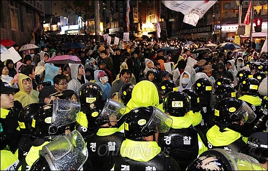 22일 저녁 서울 중구 명동성당 인근 차도에서 경찰들이 물대포(살수차)를 동원해 시위 참가자들을 강제해산시키자, 인도로 올라간 시위 참가자들이 "비준무효! 명박퇴진!" 등 구호를 외치며 경찰과 대치를 벌이고 있다.