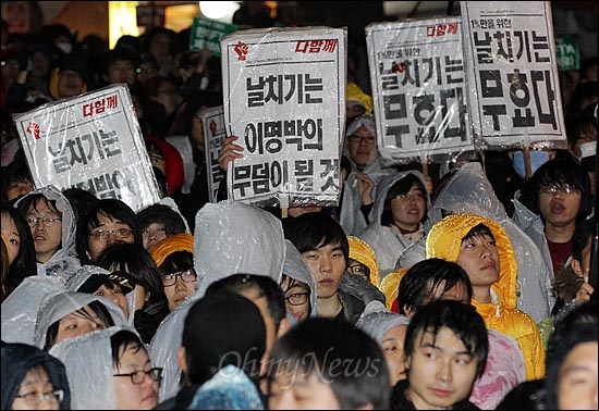 22일 저녁 서울 중구 명동성당 인근 차도에서 경찰들이 물대포(살수차)를 동원해 시위 참가자들을 강제해산시키자, 인도로 올라간 시위 참가자들이 한미FTA 비준안 한나라당 단독처리를 규탄하며 피켓을 들어보이고 있다.