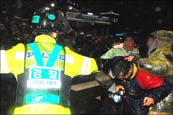 11월23일 밤 서울광장 인근에서 '한미FTA 국회비준 무효'를 외치며 시위를 벌이는 시위대 검거작전을 펼치던 경찰관 한명이 사진기자의 머리를 잡은채 강제연행을 시도하고 있다.
