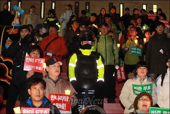  26일 오후 한미FTA 날치기 비준안 처리에 항의하는 야5당 합동 정당연설회와 촛불집회가 예정된 서울 광화문 광장을 경찰이 원천봉쇄하고 부근 세종문화회관앞 계단에도 경찰들이 배치된 가운데, 촛불을 든 시민들이 '알박기'로 자리를 선점한 경찰 주위에 모여 들고 있다.