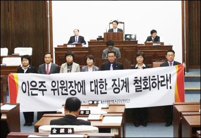 지난 14일 민주노동당 소속 7명의 울산시의원이 시의회 본회의장에서 이은주 의원 징계 철회를 요구하는 플래카드를 들고 항의하고 있다