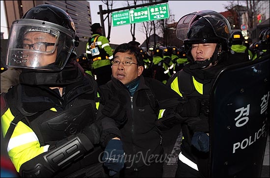 경찰이 광화문광장에서의 '한미FTA 날치기 무효 범국민 촛불대회'를 불허한 가운데, 3일 오후 서울 종로구 종로1가에서 한 집회 참가자가 '한미FTA 날치기 무효'와 '이명박 퇴진' 등을 요구하며 시위를 벌이다가 경찰에게 강제연행되고 있다.