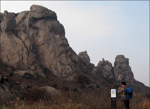 한 등산객이 월출산 큰바위얼굴의 전설이 새겨진 안내판을 보며 사진을 찍고 있다.