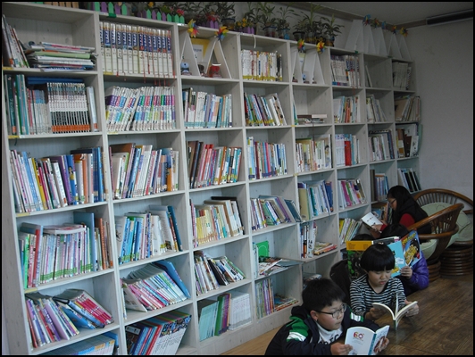 지역의 어느 기업에서 후원한 도서실 책장과 책-학생들이 자유로이 앉아 책을 읽고 있네요. 보기 좋습니다.