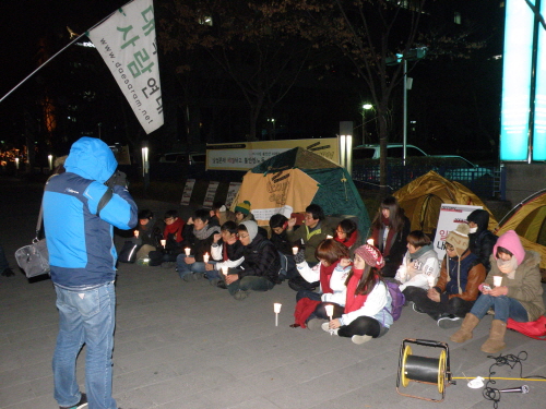 한국거래소 앞을 점령한 대학생들이 텐트앞에서 촛불시위를 벌이고 있다. 