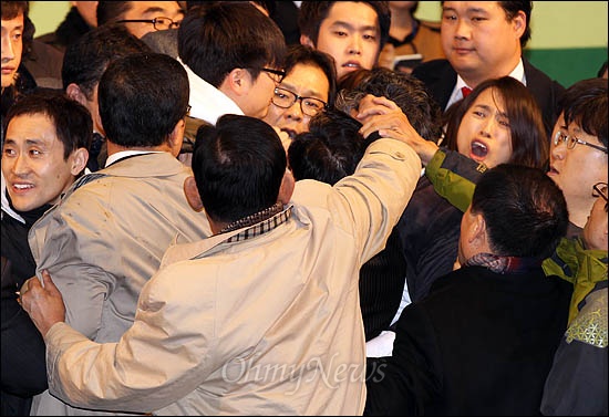 민주당이 11일 임시전국대의원대회에서 진통끝에 야권통합안 전대 가결을 선포하자 반대측 당원들이 연단에 올라 당직자의 머리채를 잡아 흔들고 있다.