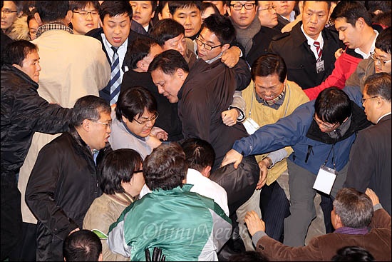 민주당이 11일 임시대의원대회에서 의결 정족수 논란끝에 야권통합안을 가결시키자 이에 반발한 통합반대파들이 연단에 올라 당직자들과 몸싸움을 벌이고 있다.