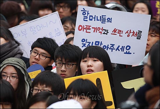 14일 오후 서울 종로구 주한 일본대사관 앞에서 열린 '제1000차 일본군 위안부 문제 해결을 위한 정기 수요집회'에 참가한 학생들이 '할머니들의 아픈 기억과 쓰린 상처를 잊지 말아주세요'라고 직접 쓴 피켓을 들어보이며 일본의 공식 사과를 촉구하고 있다.