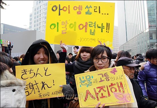 14일 오후 서울 종로구 주한 일본대사관 앞에서 열린 '제1000차 일본군 위안부 문제 해결을 위한 정기 수요집회'에 참가한 시민들이 직접 쓴 피켓을 들어보이며 일본군 위안부 범죄의 진상규명과 공식 사과를 촉구하고 있다.